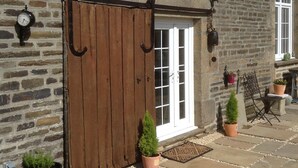 A stone building with a wooden gate, potted plants, and outdoor seating.