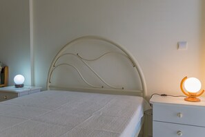Ein Schlafzimmer mit einem Bett, einem Nachttisch, einer Kommode und einer Wandleuchte.