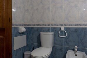 Ein Badezimmer mit Toilette, Waschbecken und einem Händetrockner.