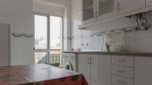 Eine Küche mit Waschmaschine, Schränken und einem Tisch mit Tischdecke.