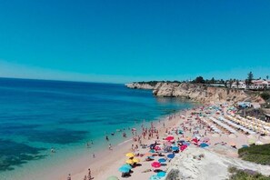 Ein Strand mit Menschen, Sonnenschirmen und Gebäuden im Hintergrund.
