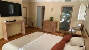 A bedroom with a large bed, a desk, a dresser, a chair, and a television. - Exceptional villa in Provence's Luberon region with a pool and breathtaking views (CAVAILLON)