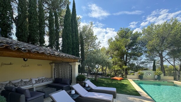 A poolside area with wicker lounge chairs, a covered seating area, and a swimming pool. - Exceptional villa in Provence's Luberon region with a pool and breathtaking views (CAVAILLON)