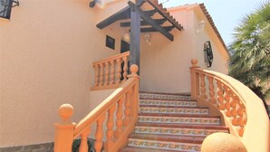 Eine Treppe mit aufwendiger Balustrade und dekorativen Fliesen führt zu einer Tür mit schwarzem Rahmen.