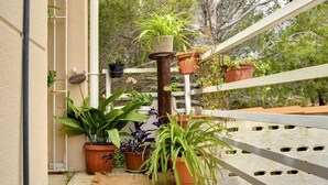 Un balcon agrémenté de plantes en pot, un poteau en bois et une balustrade blanche.