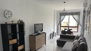 A modern living room with a television, sofa, and a small table. - Casa Jandía is an apartment with terrace in the center and 100 meters from the beach. (Morro Jable)