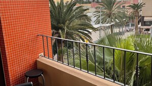 A balcony with red tiled walls, a metal railing, and a view of palm trees and buildings in the distance. - Casa Jandía is an apartment with terrace in the center and 100 meters from the beach. (Morro Jable)