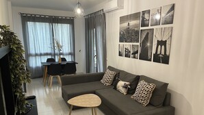 A modern living room with a grey sofa, a small wooden table, and a dining area with a black table and chairs. - Casa Jand ía is an apartment with terrace in the center and 100 meters from the beach. (Morro Jable)