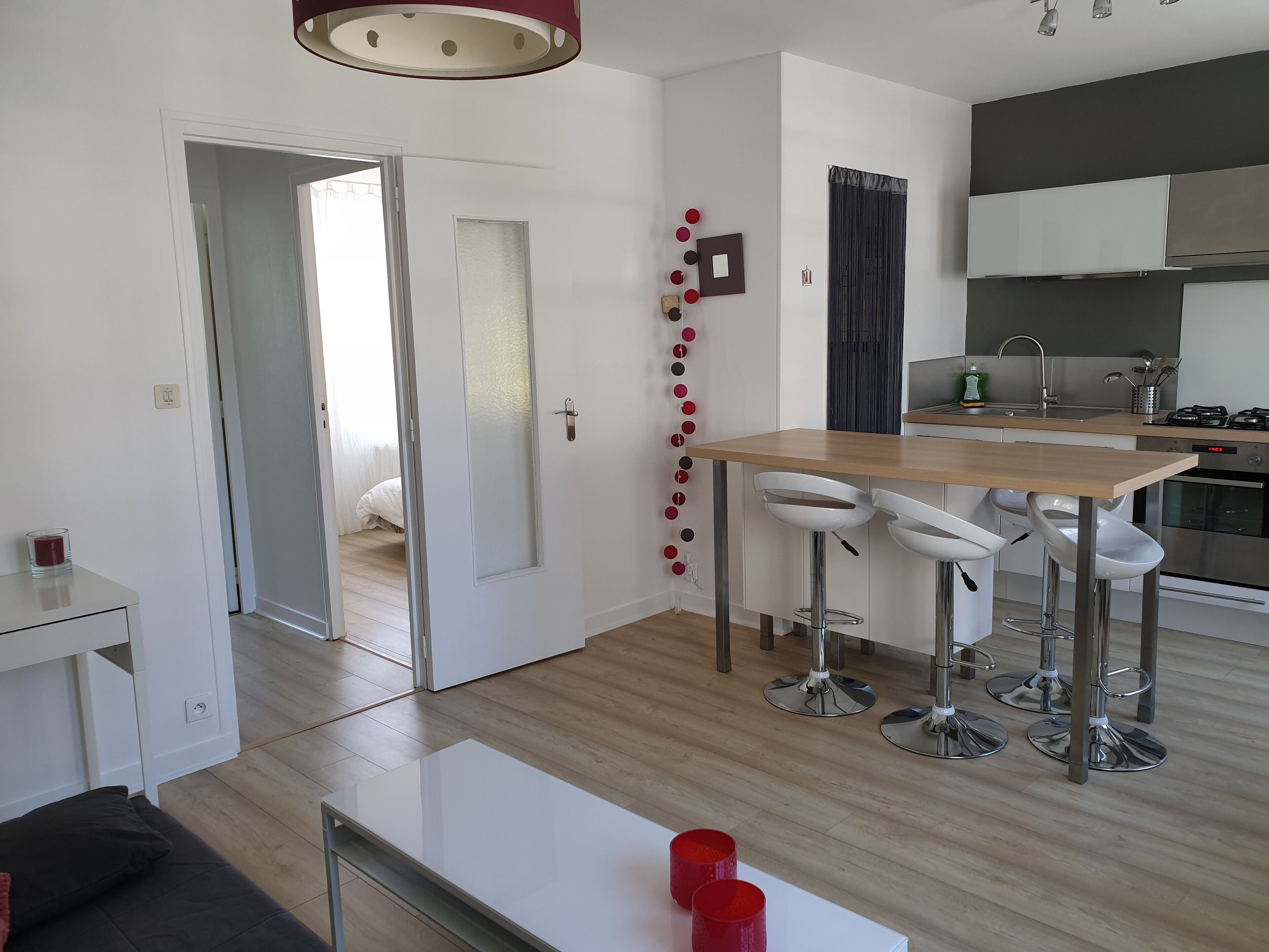 Cozinha moderna com bancada de madeira, eletrodomésticos de aço inoxidável e banquetas brancas.