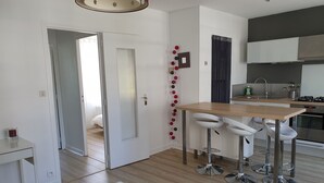 A modern kitchen with a wooden countertop, stainless steel appliances, and white bar stools. - Apartment/ flat - Saint-Malo (Saint-Malo)