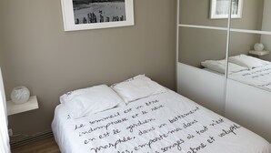 A bedroom with a bed, a bedside table, a mirror, and a framed photograph on the wall. - Apartment/ flat - Saint-Malo (Saint-Malo)