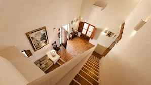 A high-ceilinged stairwell with a tiled floor, a small table with a candle, and a framed picture on the wall. - CAN NOVES-Villa with terrace and BBQ in a central and quiet area (Sant Francesc de Formentera)