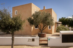 A building with a beige facade, a tree in the center, and a gate labeled "Can Noves."