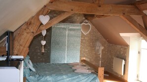 A rustic attic bedroom with a bed, wooden beams, and a stone wall. - Walnut Lodge, 1 bedroom traditional Gite in rural location  (Pleumartin)