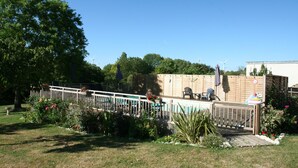 A fenced deck with a pool, surrounded by lush greenery and trees. - Walnut Lodge, 1 bedroom traditional Gite in rural location  (Pleumartin)