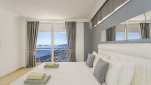 A hotel room with a large bed, a view of the sea, and a balcony.