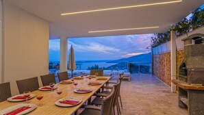 An outdoor dining area with a view of the sea and mountains.