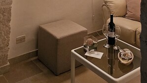 A cozy room with a stone archway, a decorative light fixture, a cushioned bench, a glass coffee table with a bottle and glasses, and a sofa with cushions. - Dimora Maria Chiara with panoramic terrace and sea view (ostuni)