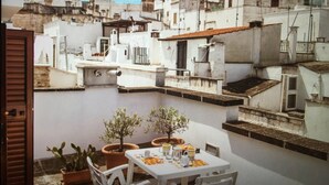 A courtyard with a table set for dining, surrounded by potted plants and white chairs. - Dimora Maria Chiara with panoramic terrace and sea view (ostuni)