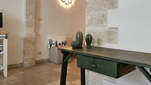 A room with a stone archway, a decorative wall light, a green table, and a cactus display. - Dimora Maria Chiara with panoramic terrace and sea view (ostuni)