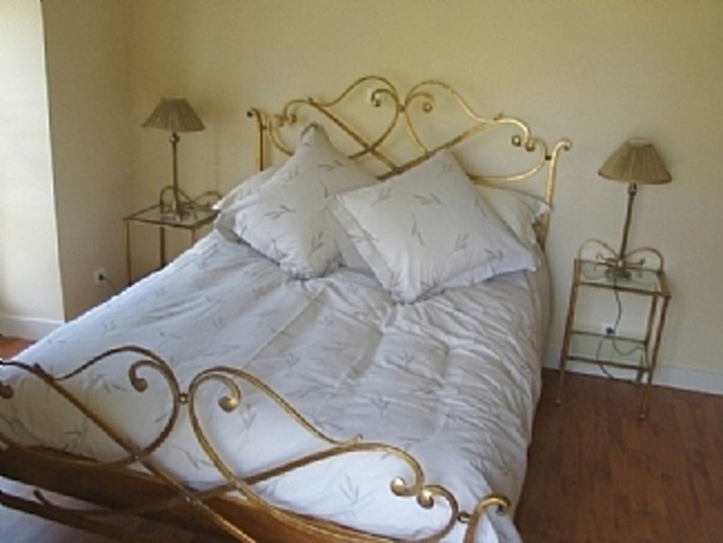A bed with a metal frame and white bedding, two bedside tables with lamps, and a wooden floor.
