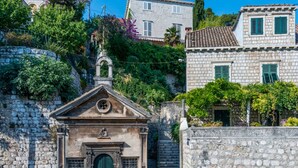 Une église en pierre avec une porte verte, entourée de murs de pierre et d’une végétation luxuriante.