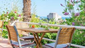 Une table en bois avec deux chaises, une vue sur la mer et un palmier.