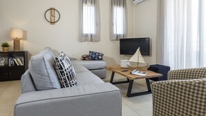A modern living room with a grey sofa, a wooden coffee table, and a flat-screen TV.