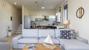 A modern living room with a light blue sofa, a wooden coffee table, and a small sailboat model.