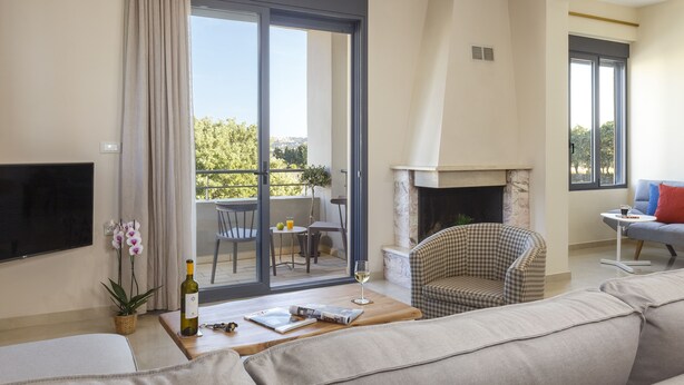 A modern living room with a sofa, a checkered armchair, a fireplace, and a balcony with a table and chairs.