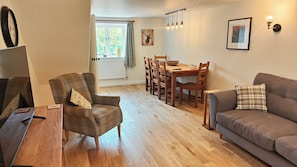 Un salon comprenant un canapé, un fauteuil, une table à manger et des chaises.
