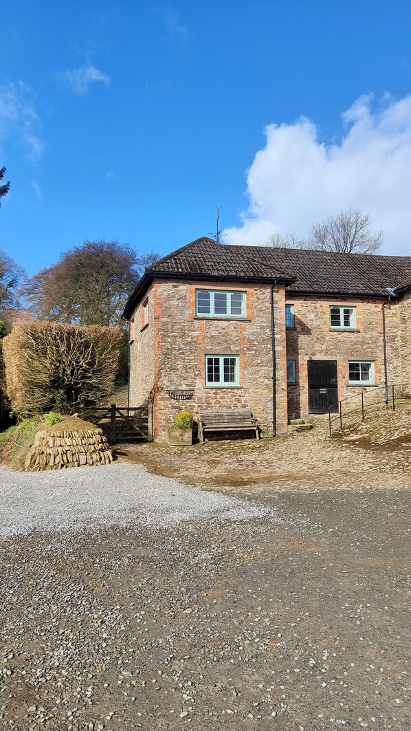 A stone building with a tiled roof, a gravel driveway, and a wooden bench. - Beautifully located in the middle of Exmoor (Exford)