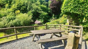 A wooden deck with a picnic table and benches, surrounded by a wooden fence and gravel ground. - Beautifully located in the middle of Exmoor (Exford)