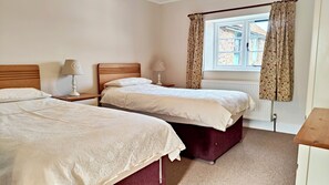 A bedroom with two beds, a window with curtains, a radiator, and a wooden headboard. - Beautifully located in the middle of Exmoor (Exford)