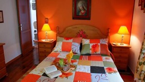 Un dormitorio con cabecera de madera, dos mesitas de noche con lámparas, colcha acolchada y un cuadro en la pared.