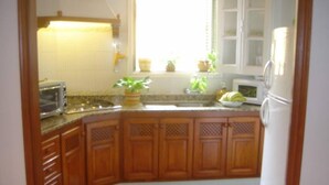 Una cocina con gabinetes de madera, microondas, tostadora y refrigerador.