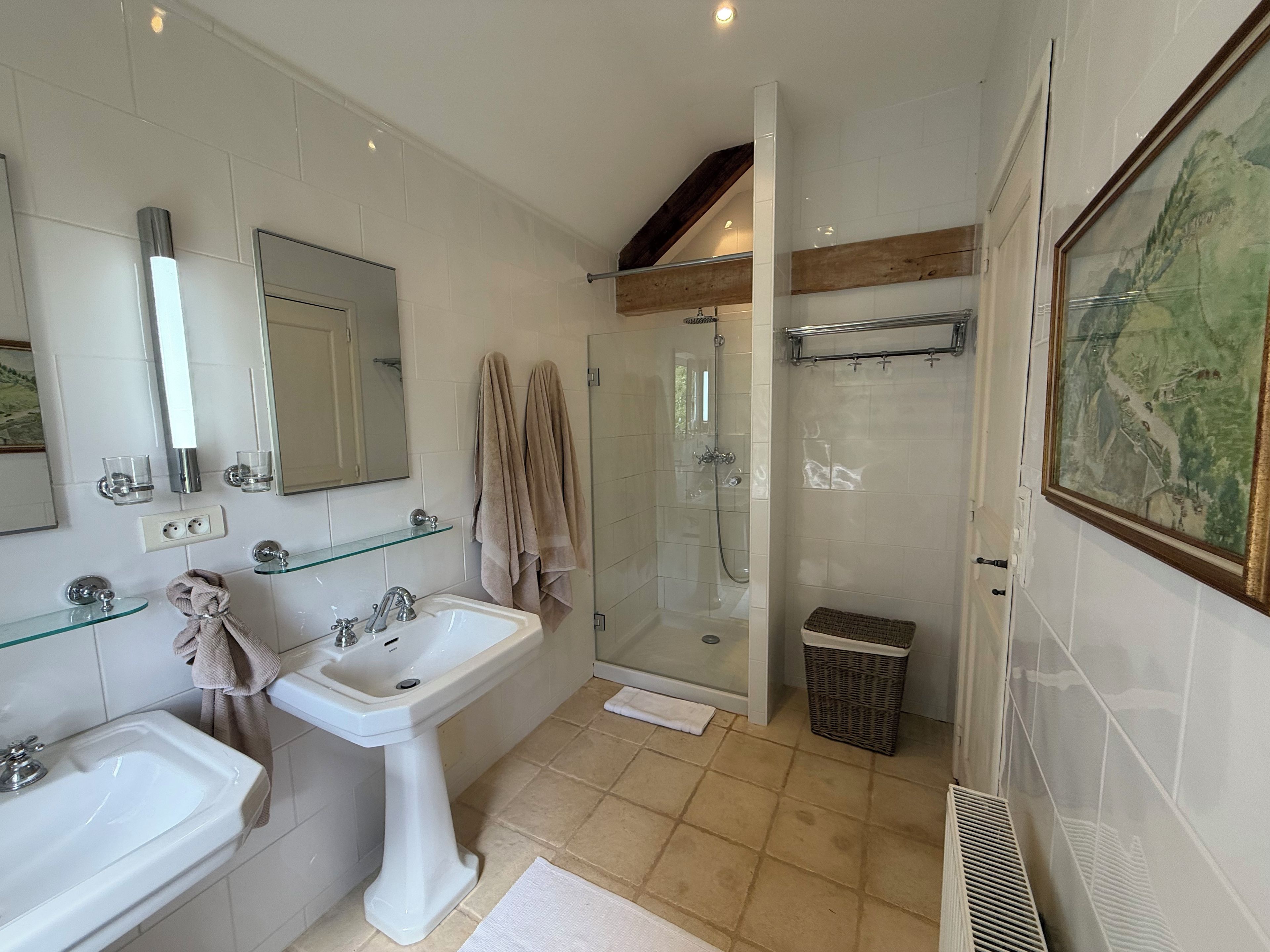 Un baño con lavamanos pedestal, cabina de ducha de vidrio y un espejo grande.