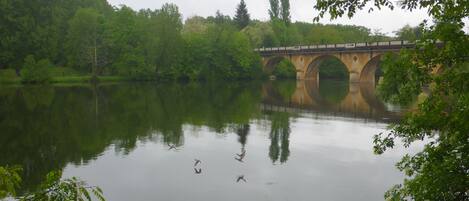 Un ponte sopra un fiume tranquillo, con i riflessi di alberi e della struttura del ponte.
