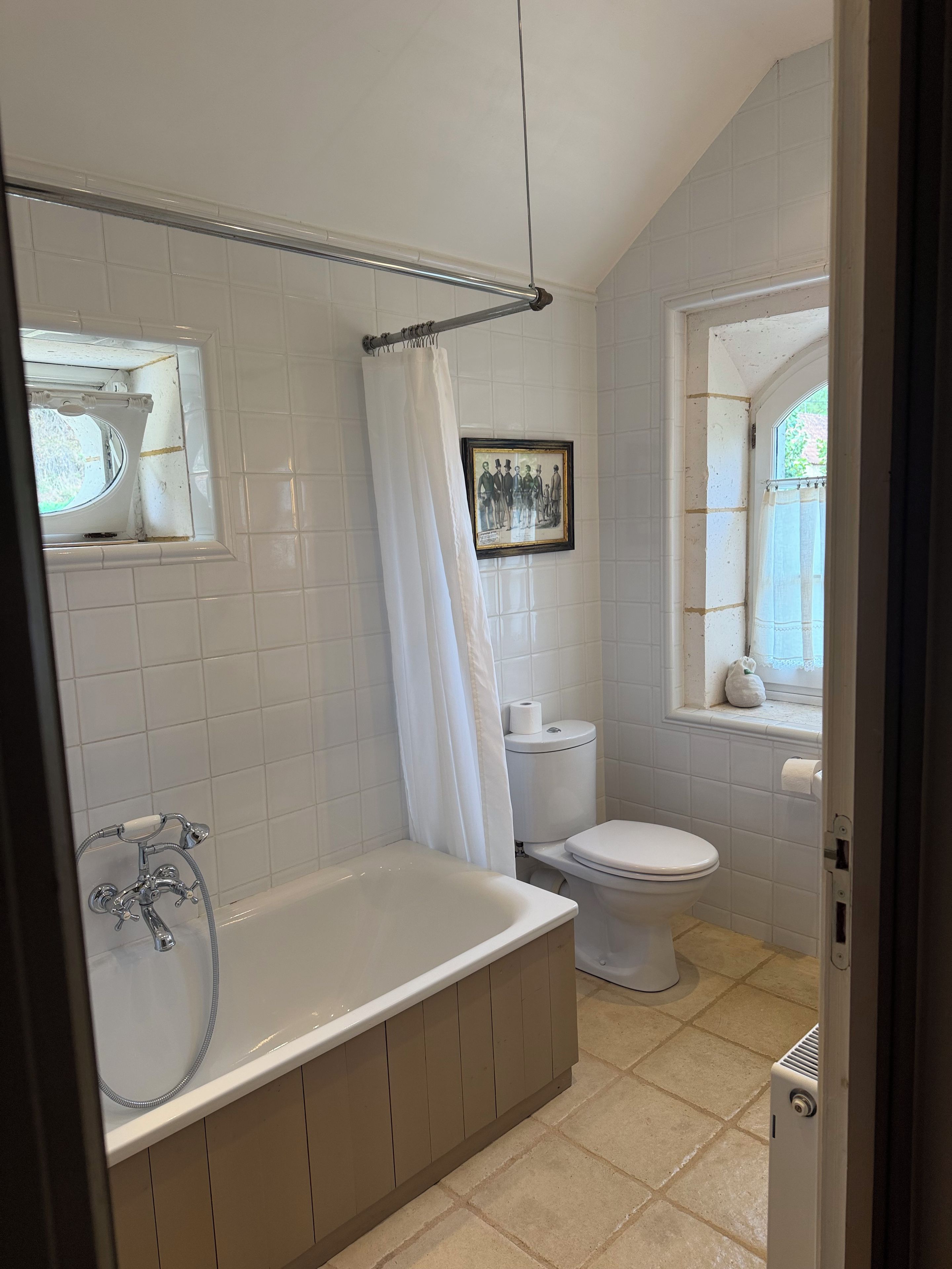 Un baño con bañera, inodoro y ventana con vistas.