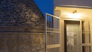 A stone building with a conical roof and a white door with a decorative glass panel. - magic and charm in a trullo  (Noci)