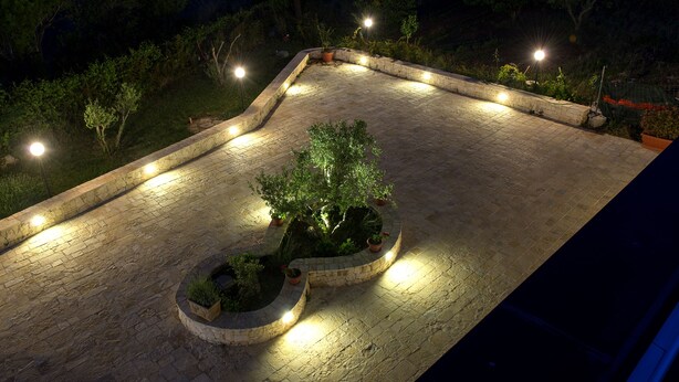An outdoor patio area with stone flooring, potted plants, and multiple light fixtures. - magic and charm in a trullo  (Noci)