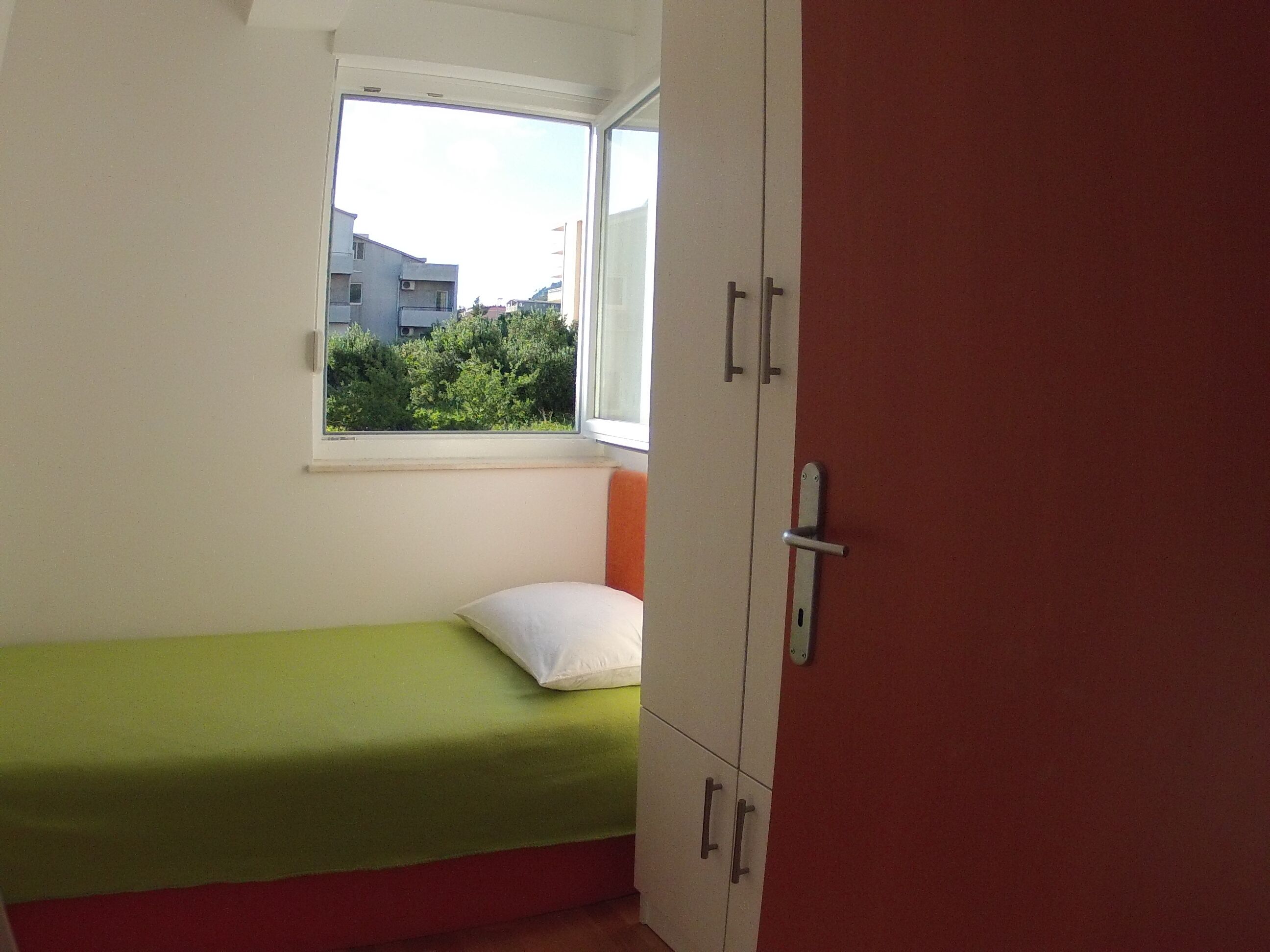 A small room with a single bed, a window, and a wardrobe.