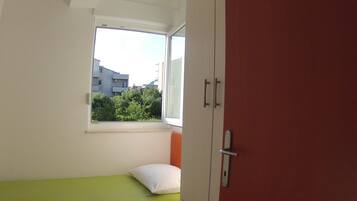 A small room with a single bed, a window, and a wardrobe.