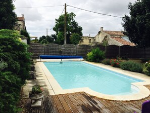 Une piscine rectangulaire entourée d’une terrasse en bois.