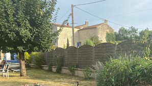 Un jardin avec un petit étang, une statue d’oiseau, un banc en pierre et un arbre.