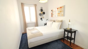 A neatly arranged bedroom with a bed, bedside table, lamp, and wall art. - Sete Rios, Near Zoo Lisboa/ free Wifi (Lisboa)