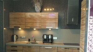 A modern kitchen with wooden cabinets, a stainless steel sink, and a coffee maker.