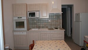 Una cocina compacta con armarios blancos, un microondas, una estufa y un refrigerador.