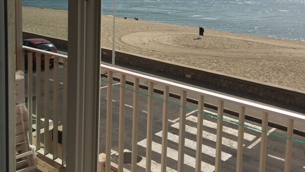Vista desde un balcón sobre una playa con cielo despejado.