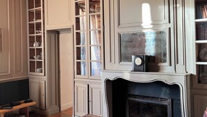 Un salon traditionnel avec une cheminée, des poutres apparentes et des meubles encastrés.